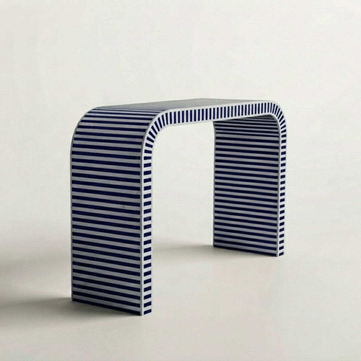 A modern U-shaped console table with a curved top, featuring a navy blue and white horizontal stripe pattern, photographed against a clean off-white background.