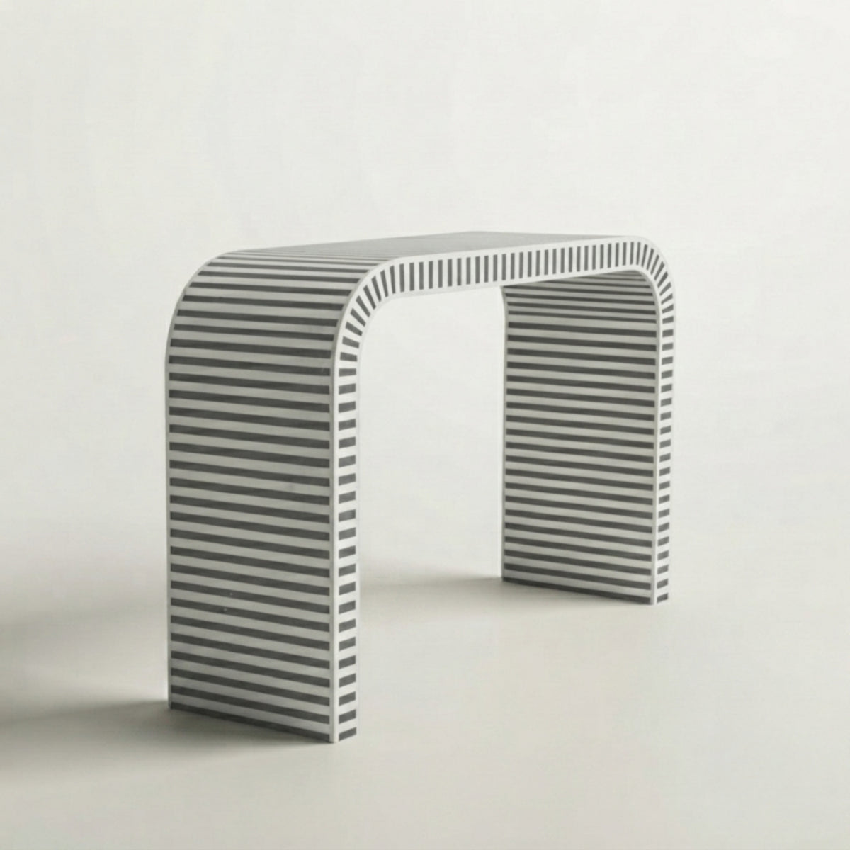 A minimalist modern console table with a curved top and striped gray and white slatted legs, set against a clean off-white background.