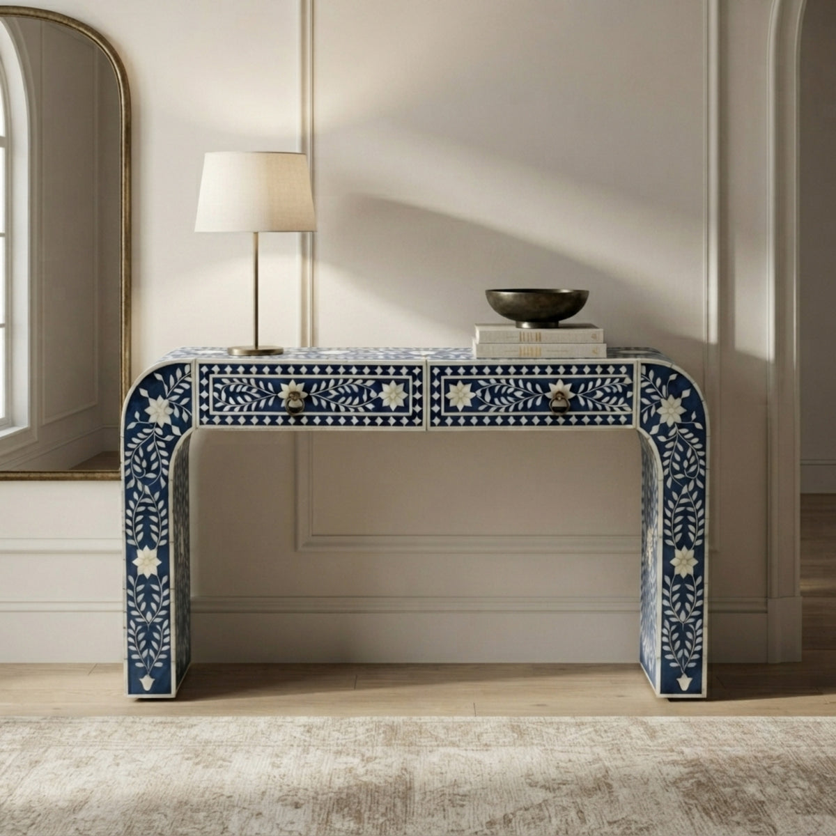 A blue and white bone-inlay console table with two drawers, styled in a bright, modern room with a table lamp and a bowl on top.