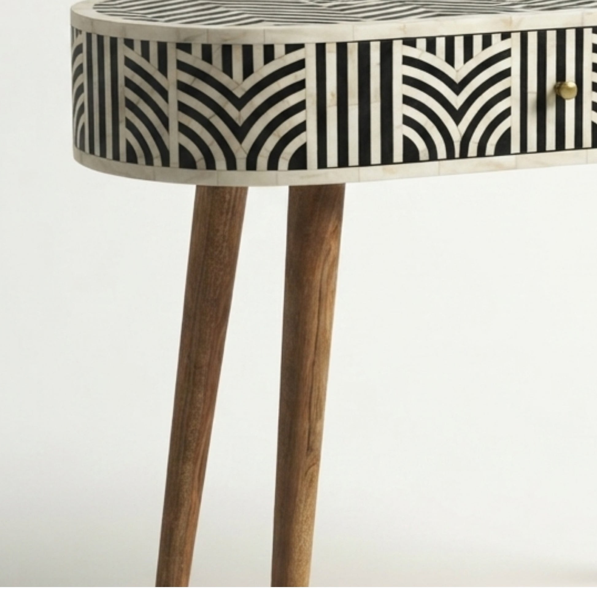 A close-up of a modern console table with a black and white geometric bone-inlay pattern on the drawer front and a natural wood finish on the legs.