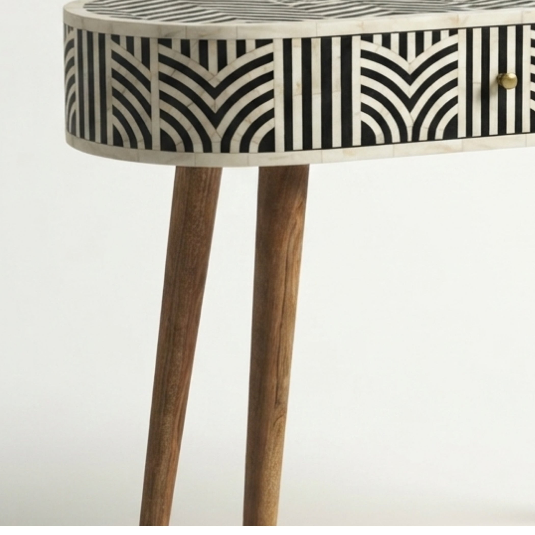 A close-up of a modern console table with a black and white geometric bone-inlay pattern on the drawer front and a natural wood finish on the legs.