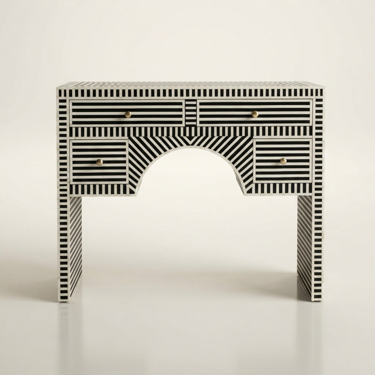 A console table with a black and white striped bone-inlay pattern and small gold drawer pulls, photographed against a clean off-white background.