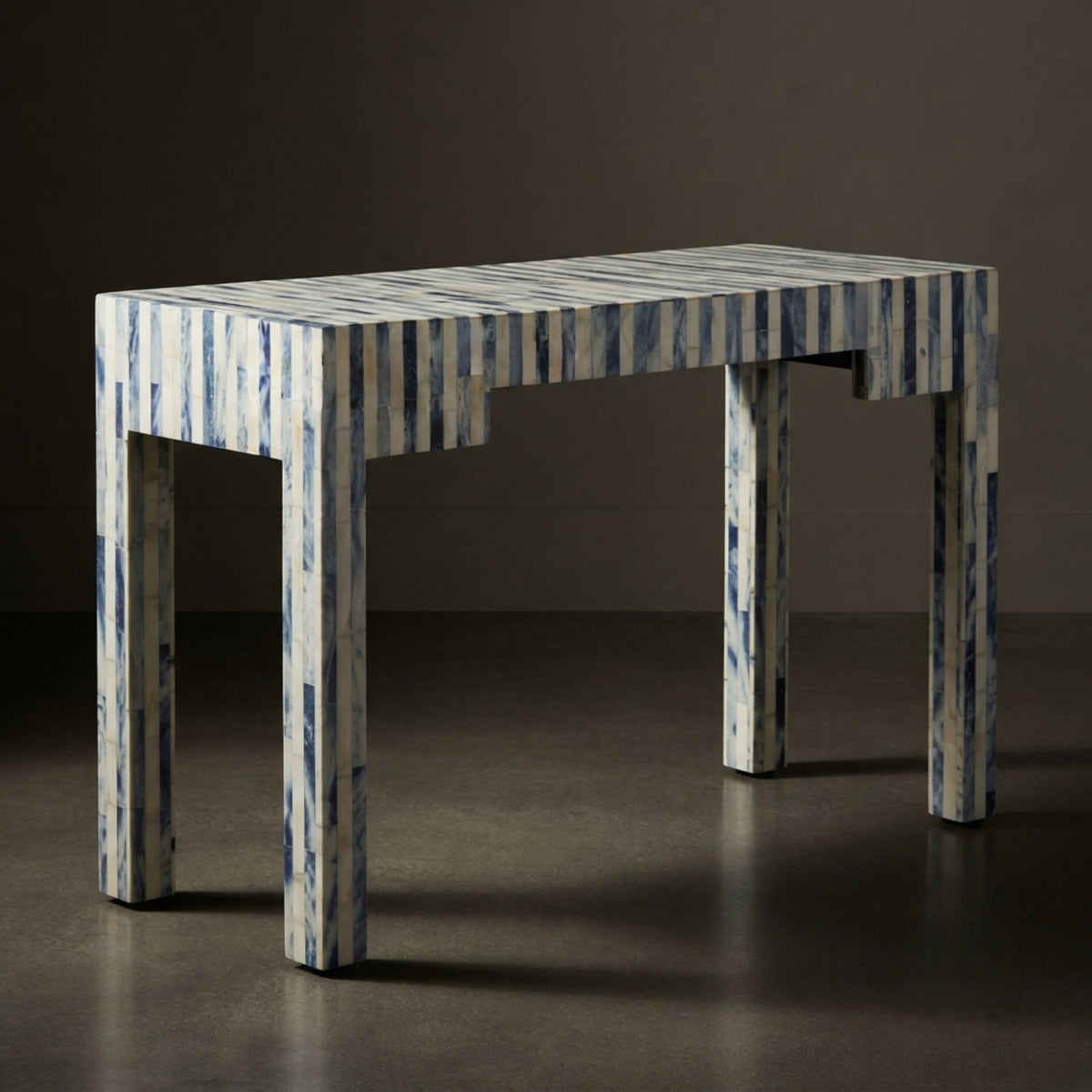 A rectangular table with a blue and white striped bone-in-shell finish, set against a dark brown studio background.