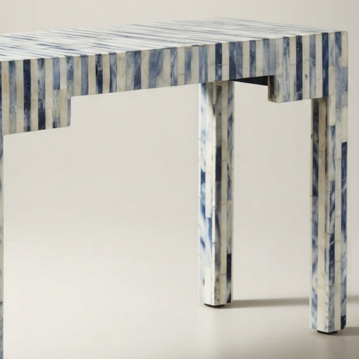 A close-up of a table with a white and blue marbled pattern, likely made from bone or horn, set against a plain light beige background.