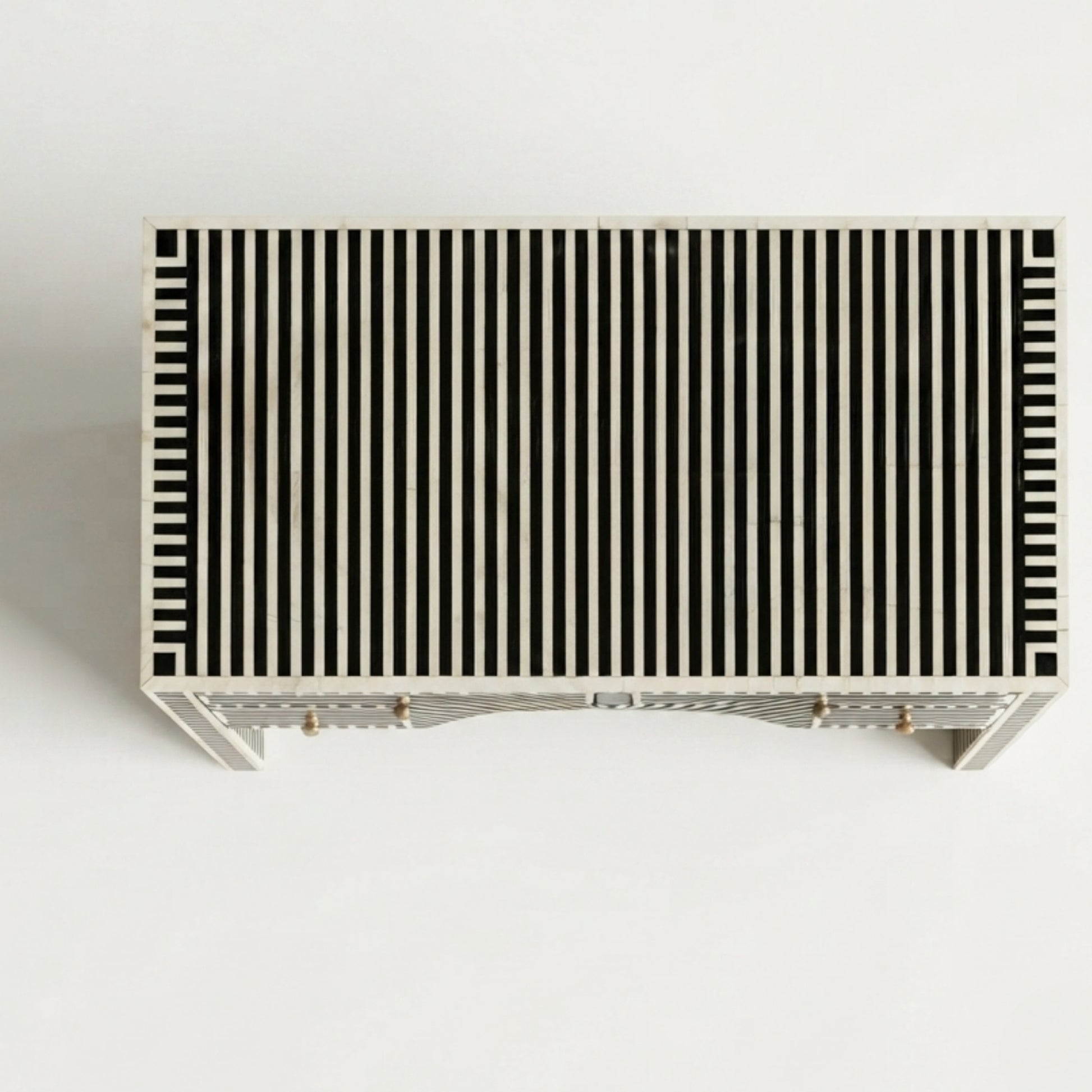 A rectangular console table with a black and off-white vertical striped pattern on the top, supported by a light-colored frame with small brass-toned legs, shown against a plain white background.