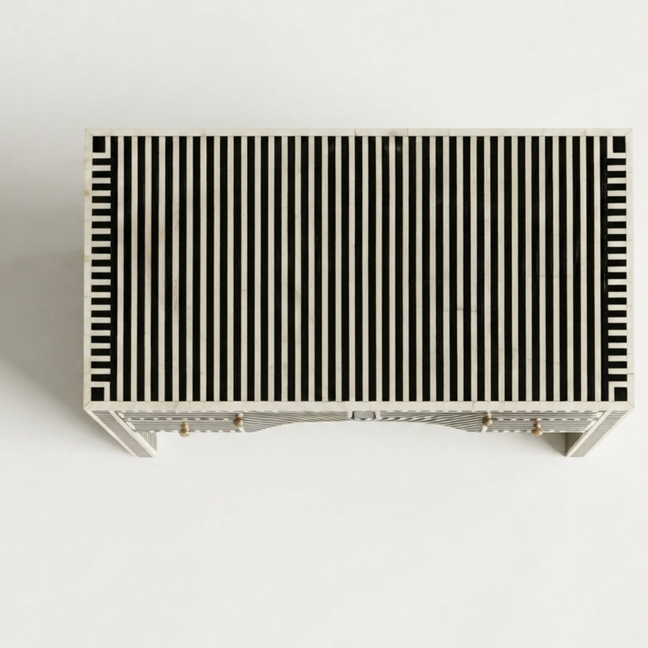A rectangular console table with a black and off-white vertical striped pattern on the top, supported by a light-colored frame with small brass-toned legs, shown against a plain white background.