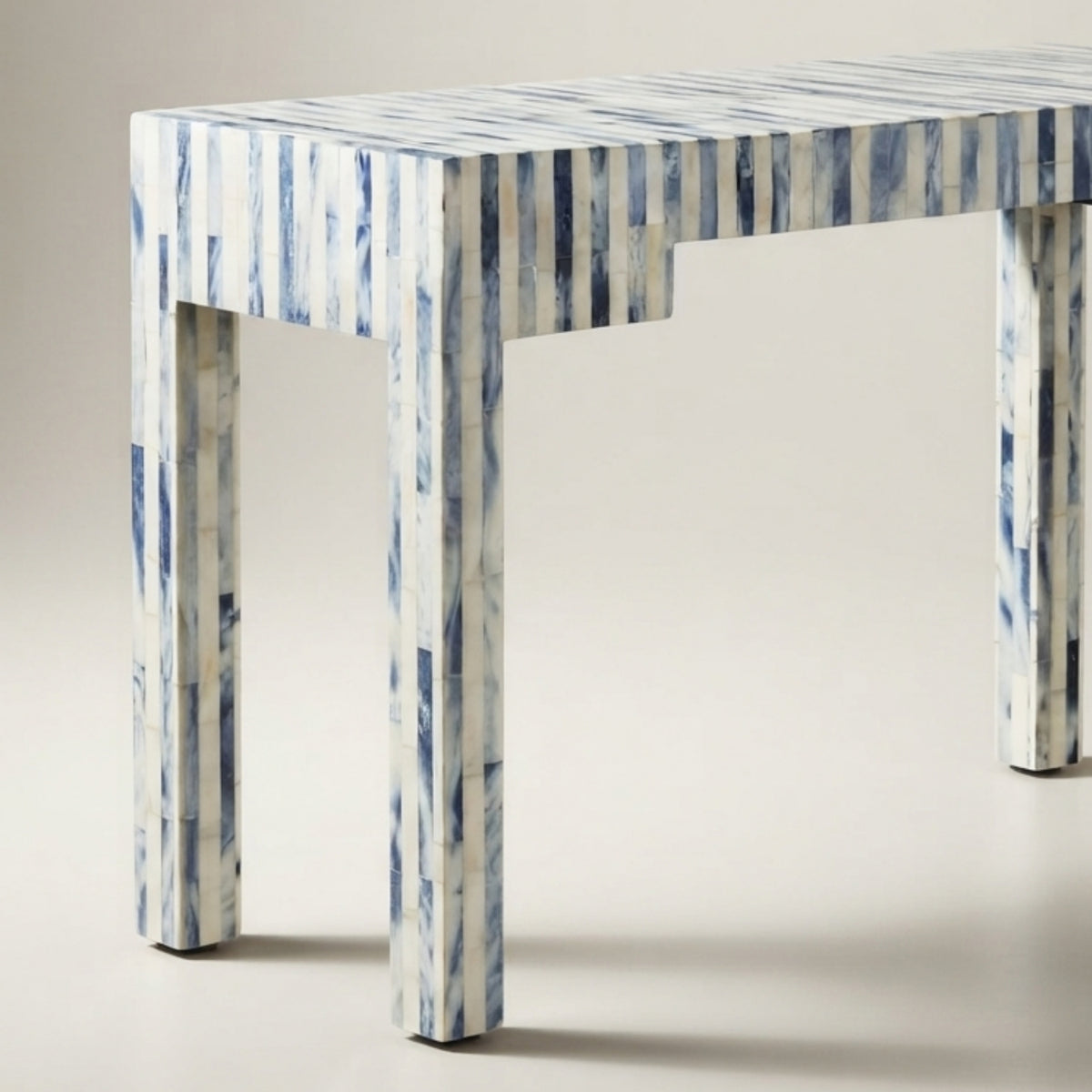 A rectangular console table with a white and blue striped bone-in-shell finish, shown from a three-quarters angle against a neutral beige background.