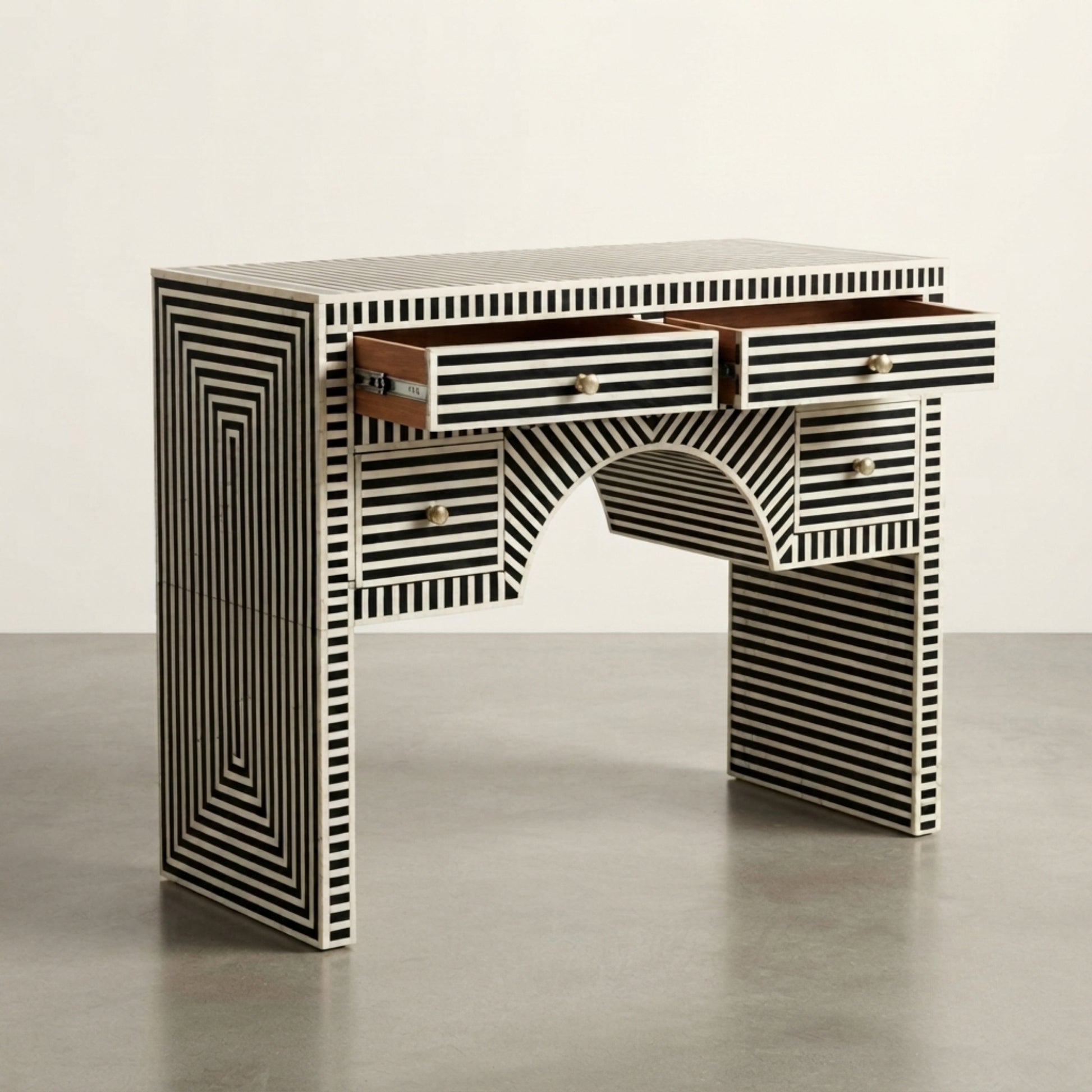 A modern writing desk with a black and white striped bone-in-lambe design, featuring multiple drawers and an open center shelf, set against a neutral studio background.