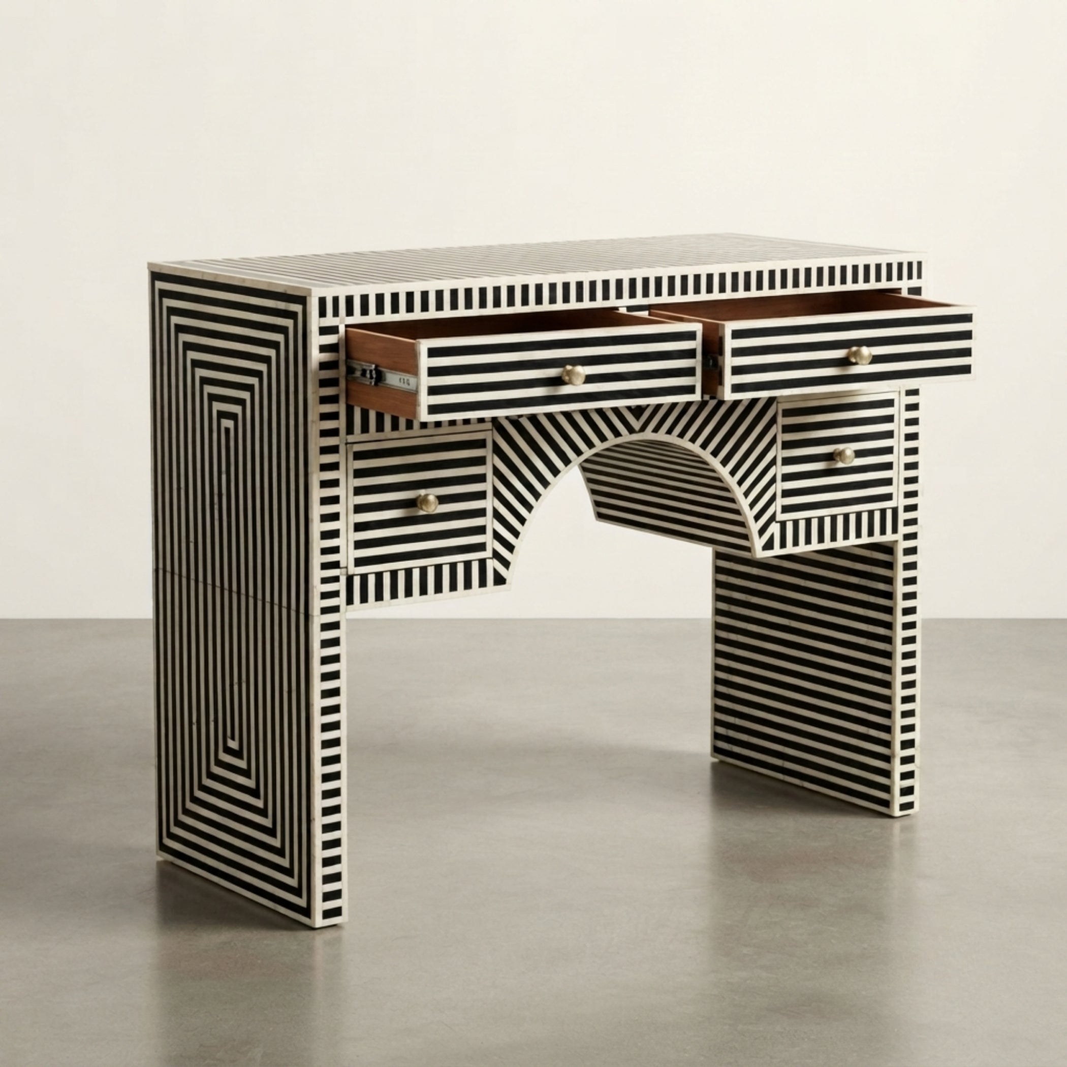 A modern writing desk with a black and white striped bone-in-lambe design, featuring multiple drawers and an open center shelf, set against a neutral studio background.