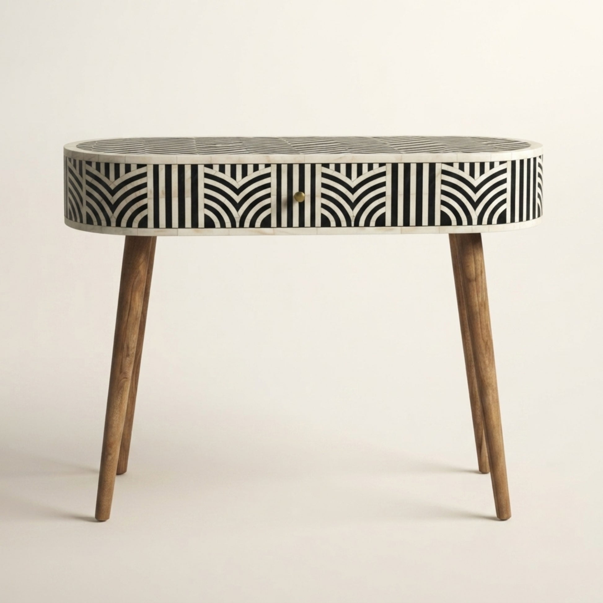 An oval console table featuring a black and white geometric bone-inlay pattern on the drawer front and top, supported by four tapered wooden legs.