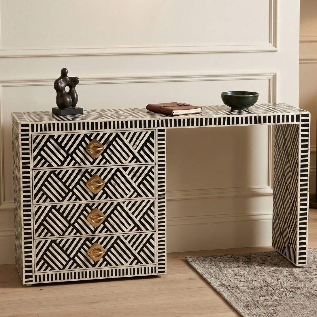 A bone-inset console table with a black and white geometric pattern, four drawers with gold handles, and open shelving, styled in a home interior setting.