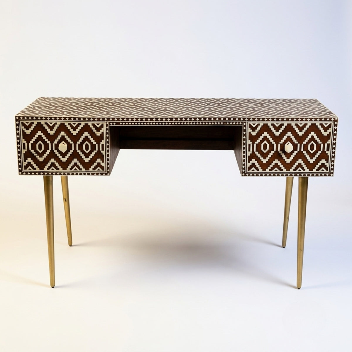 A mid-century modern writing desk featuring a brown and beige geometric bone inlay pattern on the top and drawer fronts, supported by four slim gold-finished metal legs.