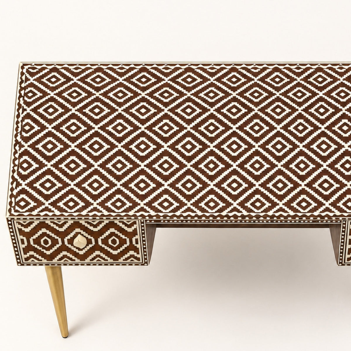 A modern console table featuring a brown and cream geometric bone-inlay pattern on the top and drawer front, with light wood legs, shown against a plain off-white background.