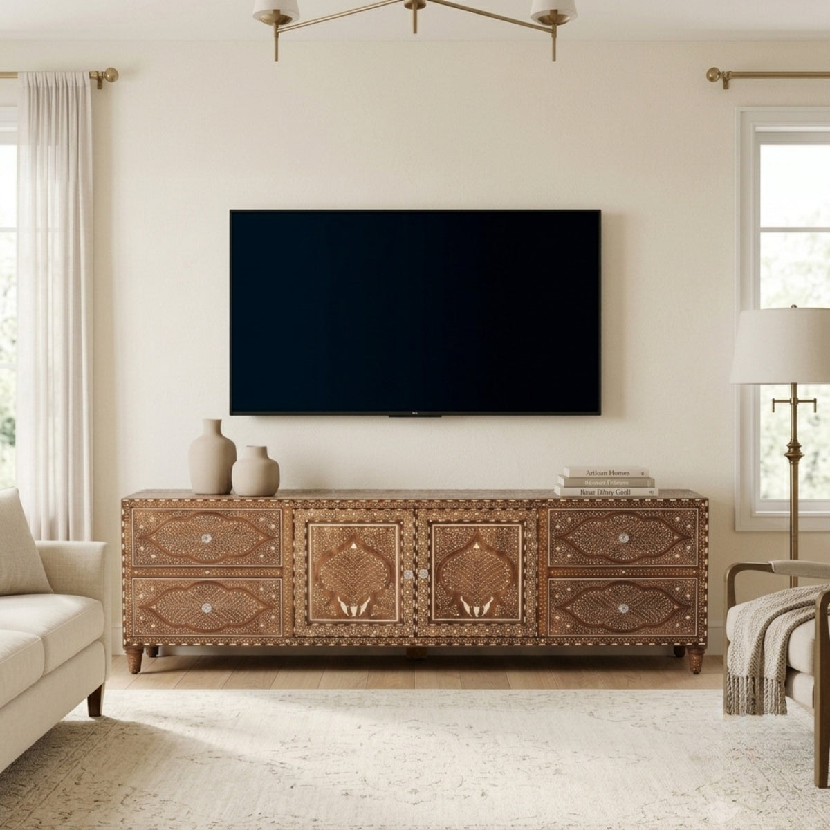A brown carved wooden TV stand or credenza with ornate geometric patterns and metal studs, styled in a bright living room with a black flat-screen TV mounted above it.