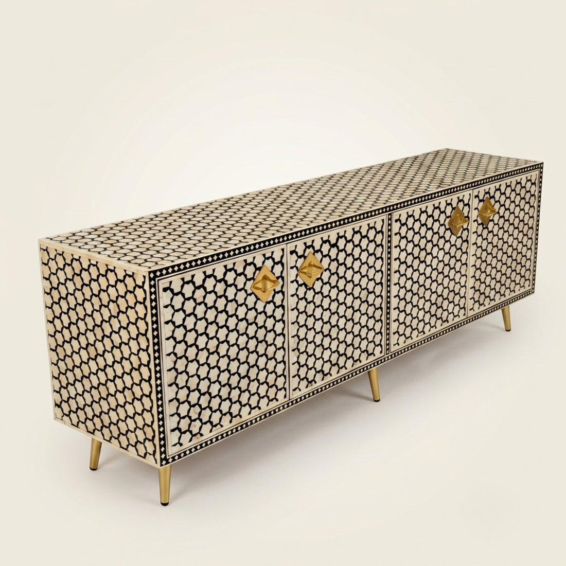 A long sideboard cabinet with a black and beige geometric bone-inlay pattern, featuring four doors with gold-tone medallion handles and slim gold legs, shown on a light beige background.