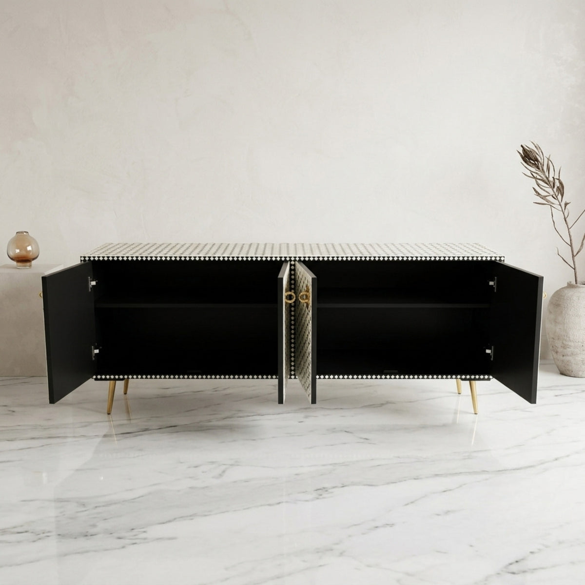 A modern black sideboard cabinet with open doors, a striped top, and gold legs, set against a light gray marble floor and textured wall.