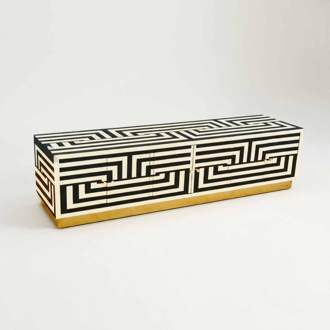 A rectangular sideboard cabinet with a black and off-white Greek key geometric pattern and a gold base, photographed on a clean white studio background.