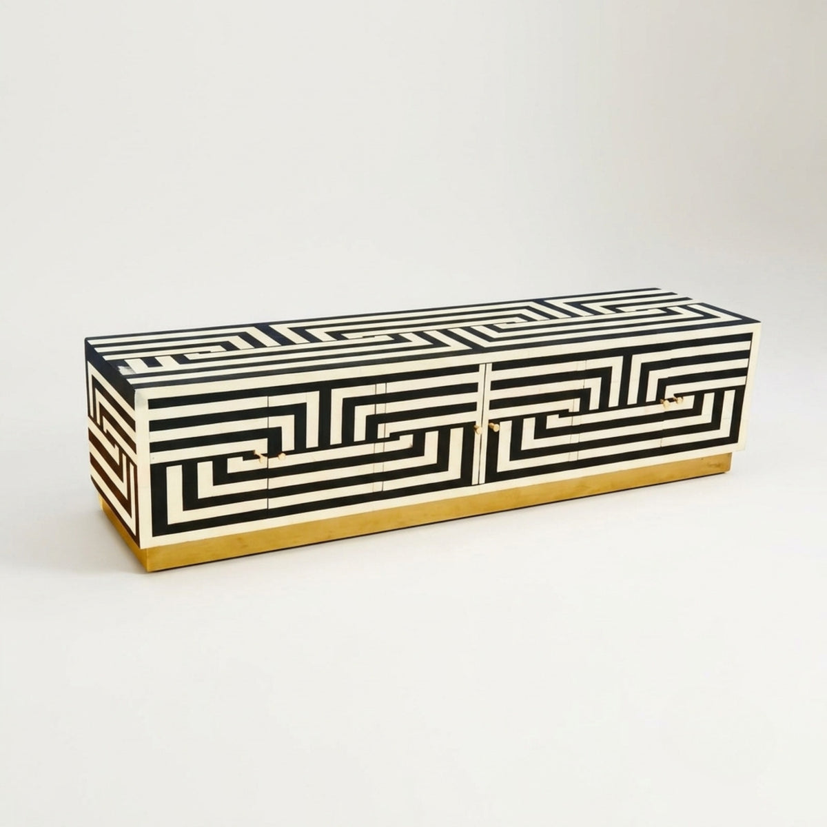 A rectangular sideboard cabinet with a black and off-white Greek key geometric pattern and a gold base, photographed on a clean white studio background.