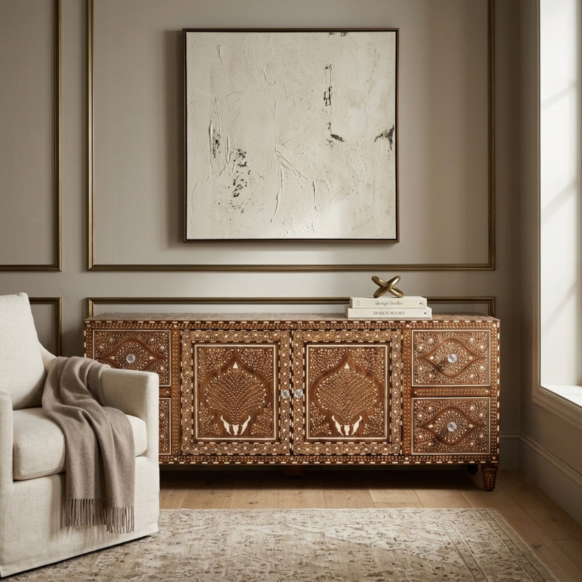 An ornate brown wooden sideboard cabinet with intricate mother-of-pearl inlay, styled in a modern living room setting under a framed abstract print.