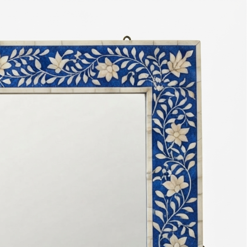 A close-up of a rectangular wall mirror with an ornate blue and white floral inlay border, shown against a plain white background.