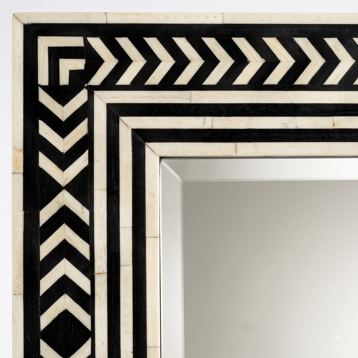 Close-up of a decorative rectangular mirror frame with a black and off-white chevron and geometric border pattern.