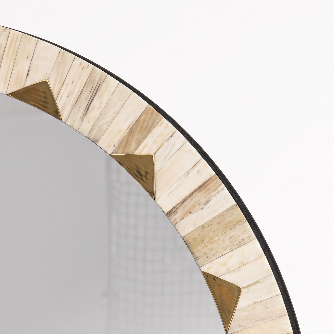 A close-up of a round wall mirror with a decorative border made of light natural wood slices arranged in a sunburst pattern, set against a plain white background.