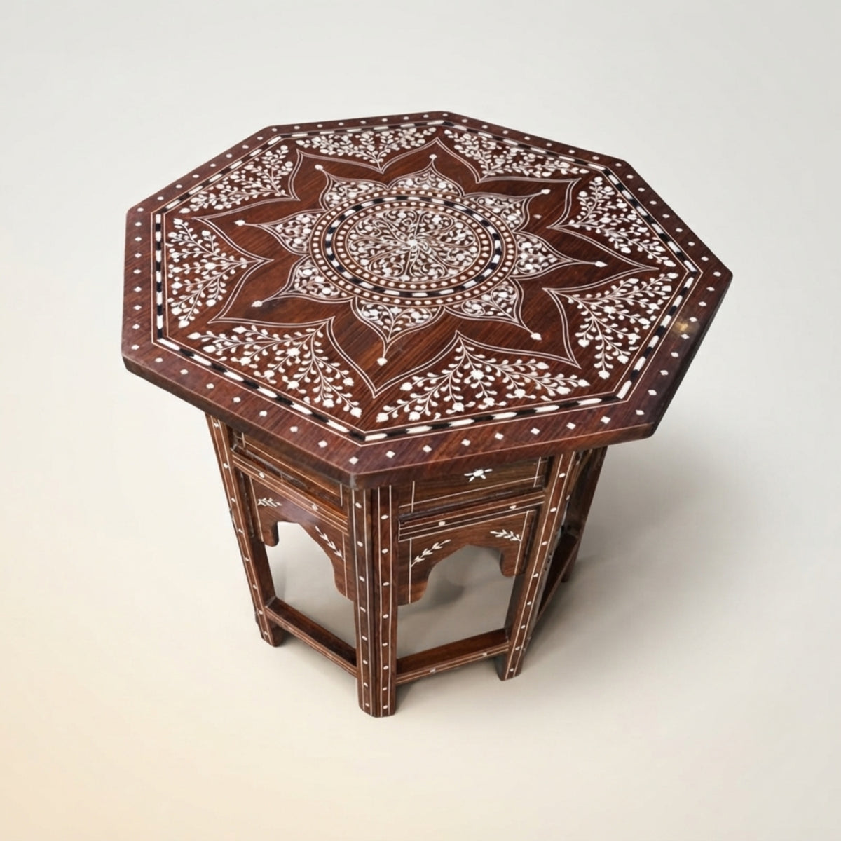 An octagonal wooden side table with intricate white bone or mother-of-pearl inlay patterns on a dark reddish-brown wood base, photographed on a light beige background.