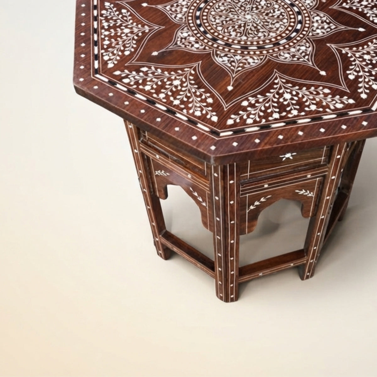 Hexagonal wooden side table with intricate white bone or mother-of-pearl inlay patterns on a dark brown wood surface, shown on a light beige background.