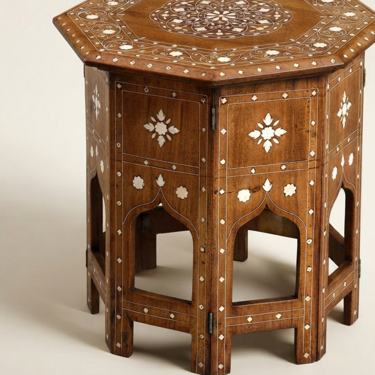An octagonal wooden side table with intricate white inlay detailing, featuring a carved circular pattern on the top, decorative panels, and arched legs on a light beige background.