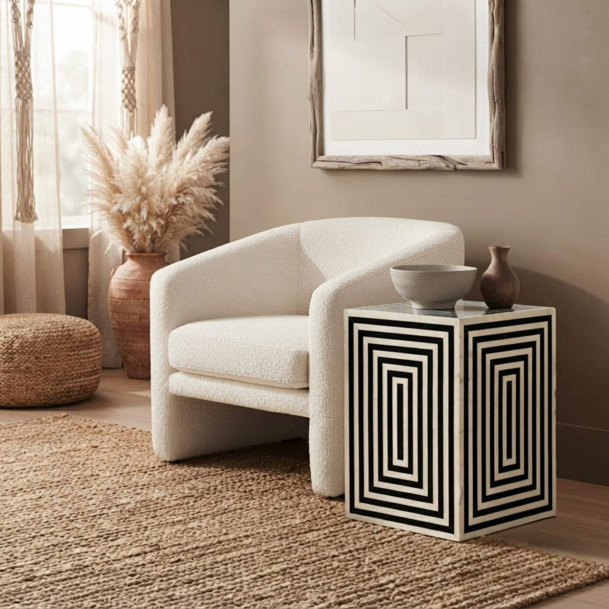 A cream bouclé armchair in a styled living room setting next to a geometric black and white side table.