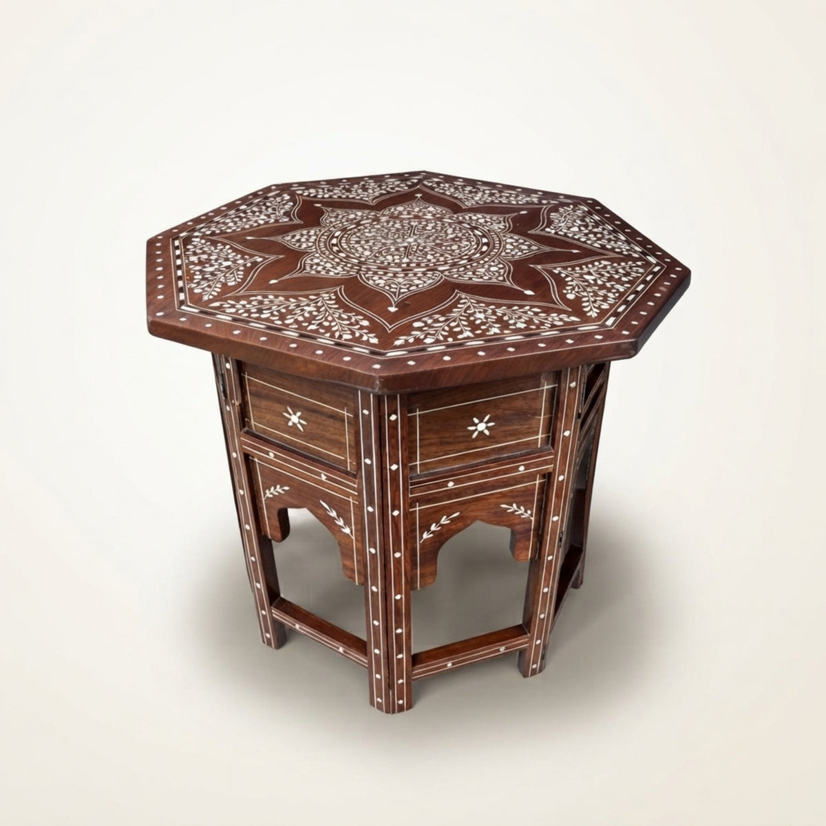A hexagonal wooden side table with intricate white bone or mother-of-pearl inlay patterns, featuring two drawers on the front with star-shaped handles, set against a plain light beige background.