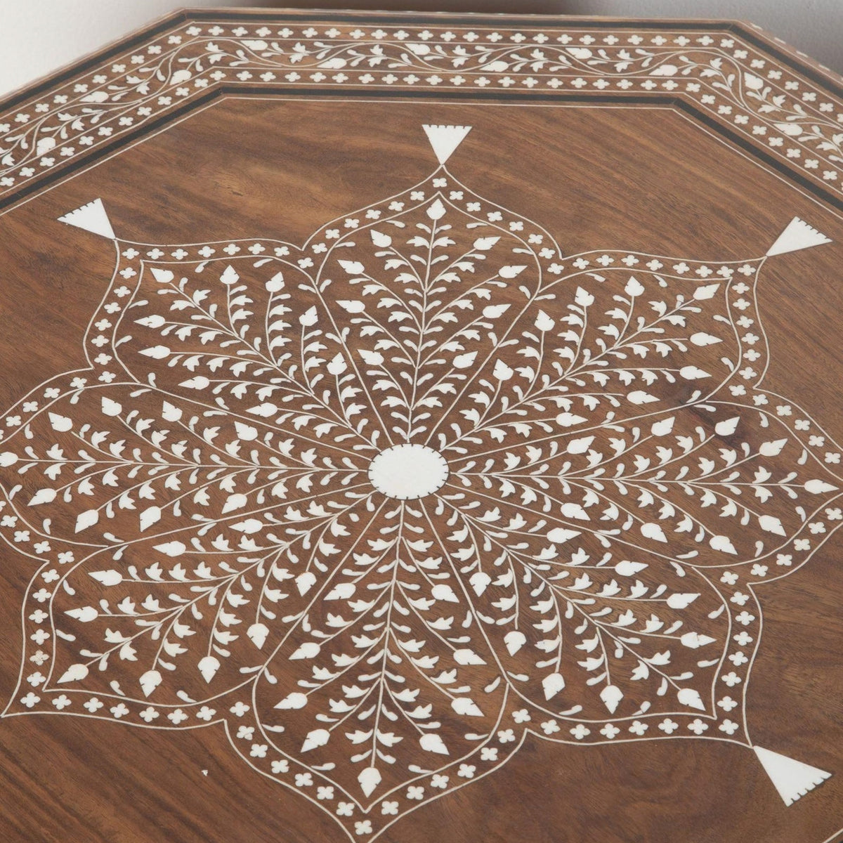 An octagonal wooden table featuring an intricate white inlay mandala design on a rich brown wood grain surface.