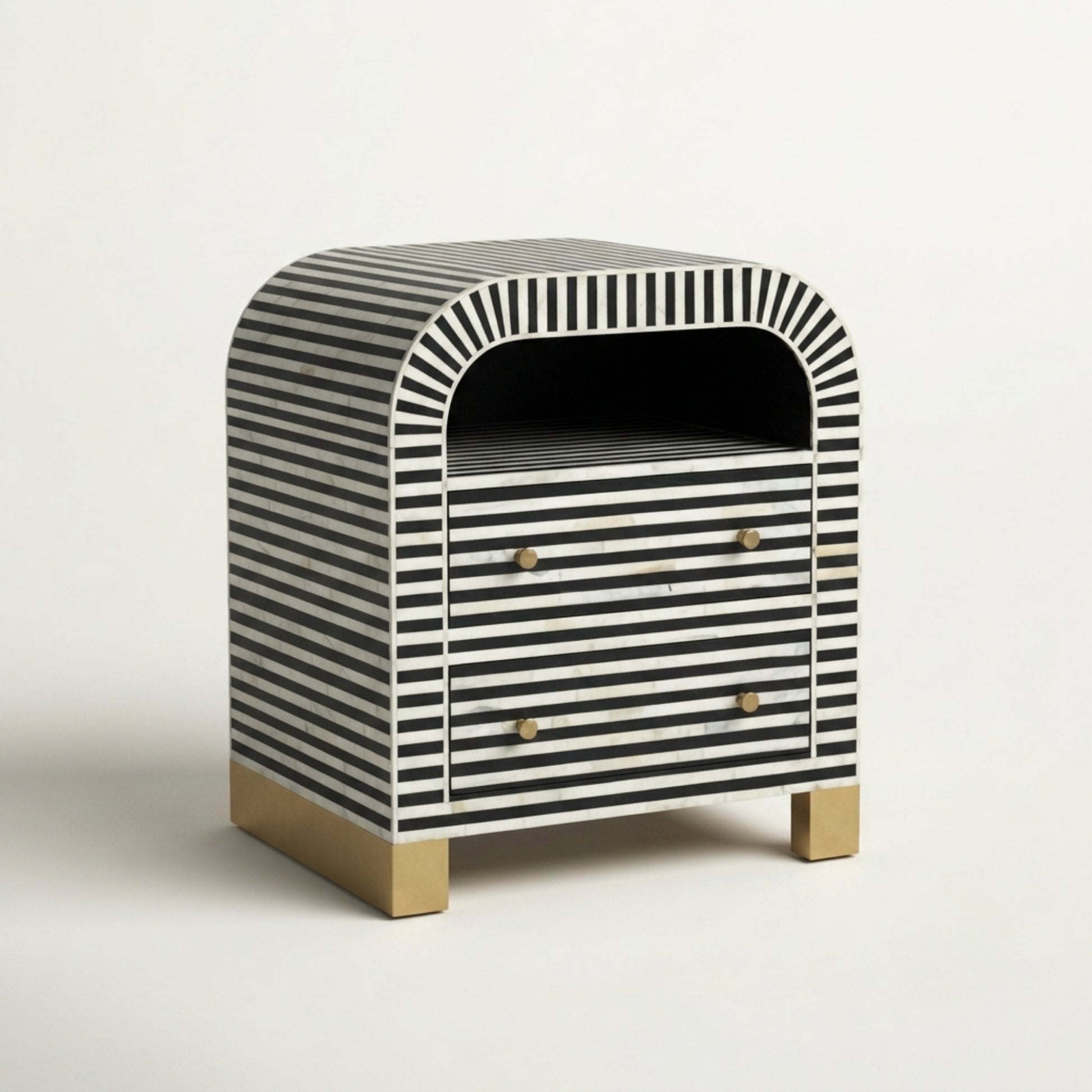 A small two-drawer nightstand with a black and white striped bone-in-lay finish, featuring a rounded top, brass drawer knobs, and a brass block base, photographed on a clean white background.