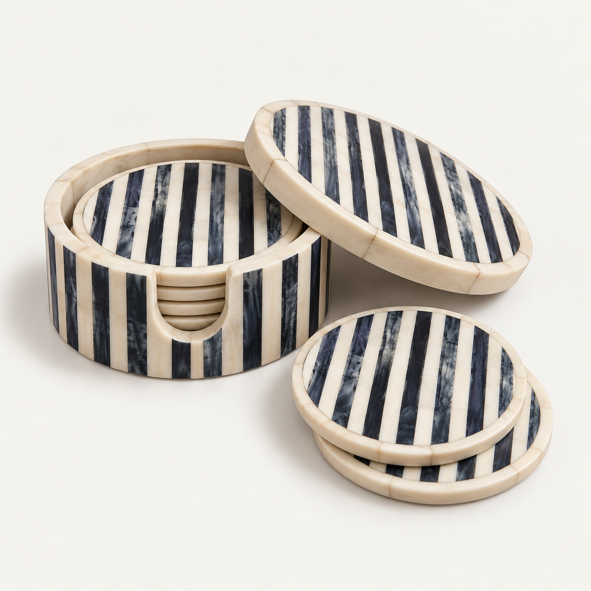 A set of round coasters and a matching round storage container with a lid, featuring alternating dark navy and cream vertical stripes, photographed on a clean off-white background.