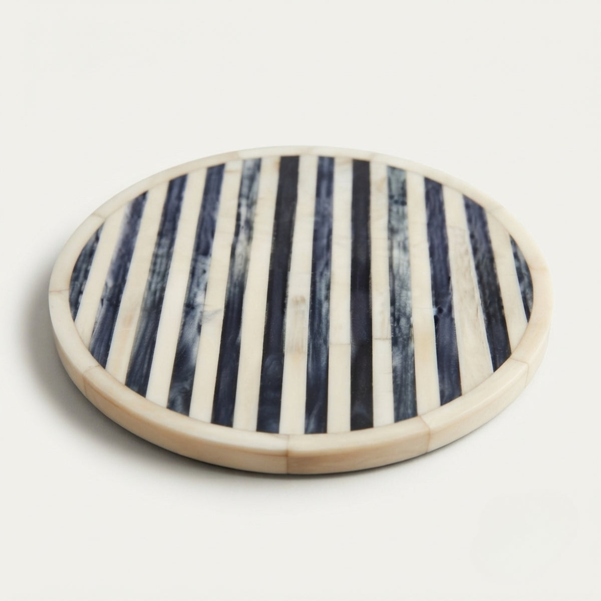 Round bone and stone striped serving board with a natural beige border, photographed on a clean off-white background.