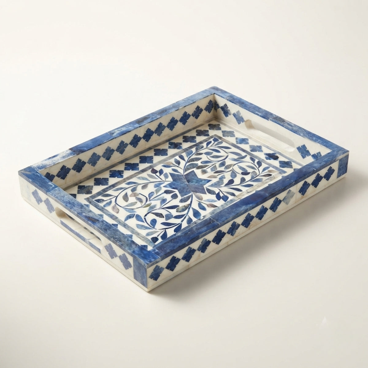 A rectangular decorative tray with a blue and white floral inlay pattern, featuring integrated side handles and a geometric border design, photographed on a light cream background.