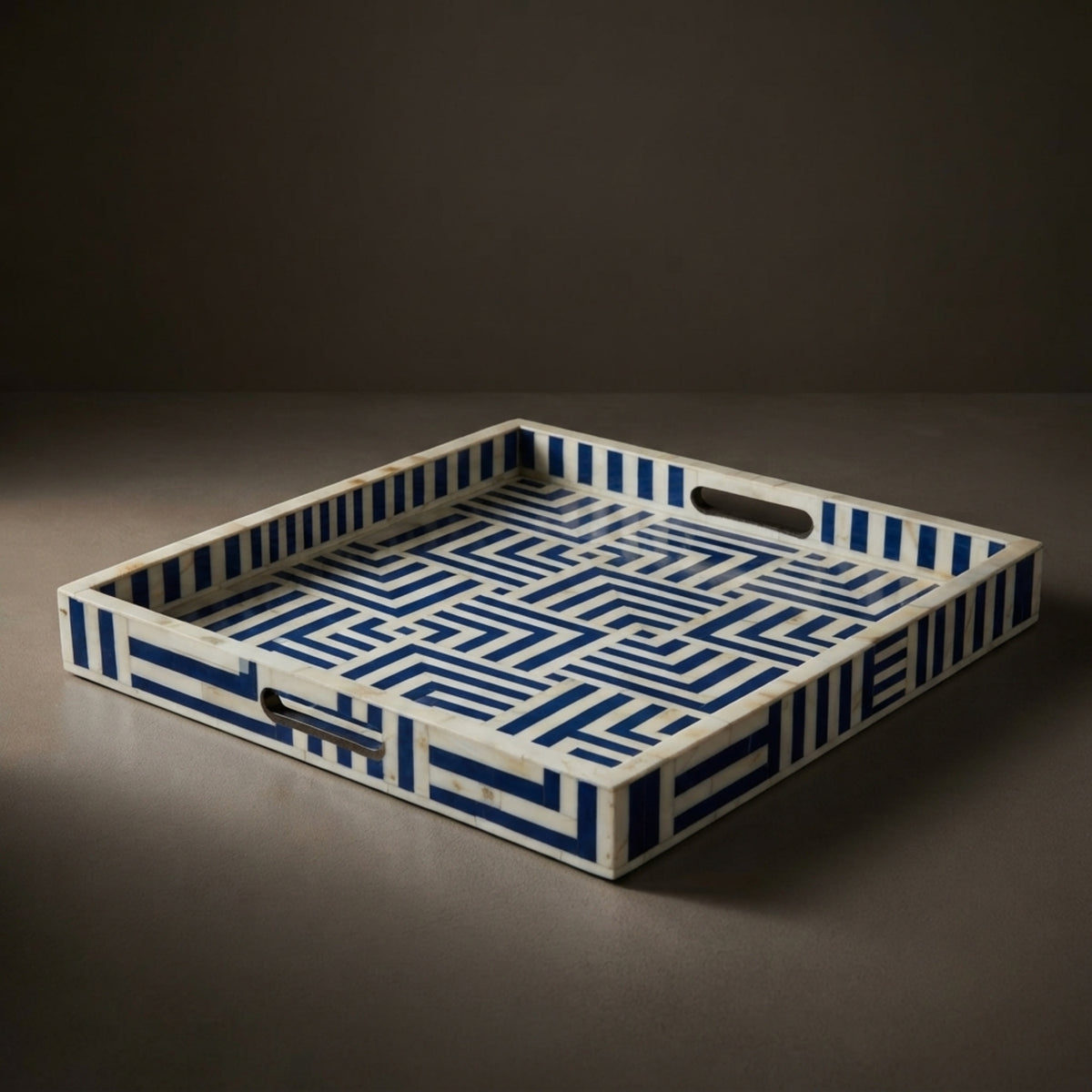 A rectangular bone tray with a geometric blue and white pattern, featuring integrated handles cutouts on the sides, set against a dark gray background.