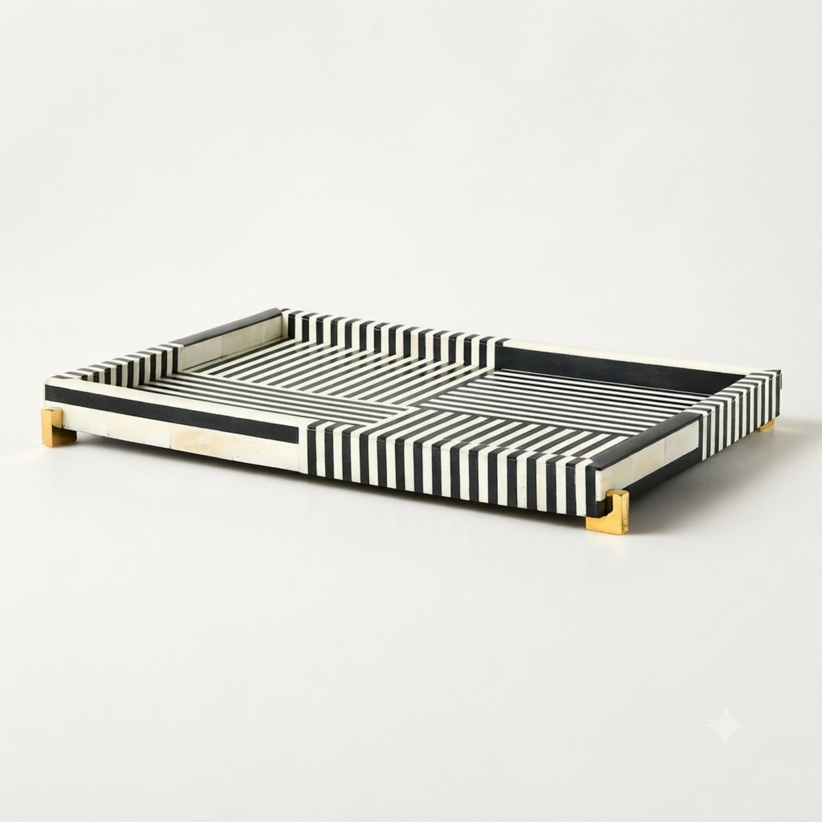 A rectangular serving tray with a black and white striped pattern and small gold metal feet, photographed on a clean white background.