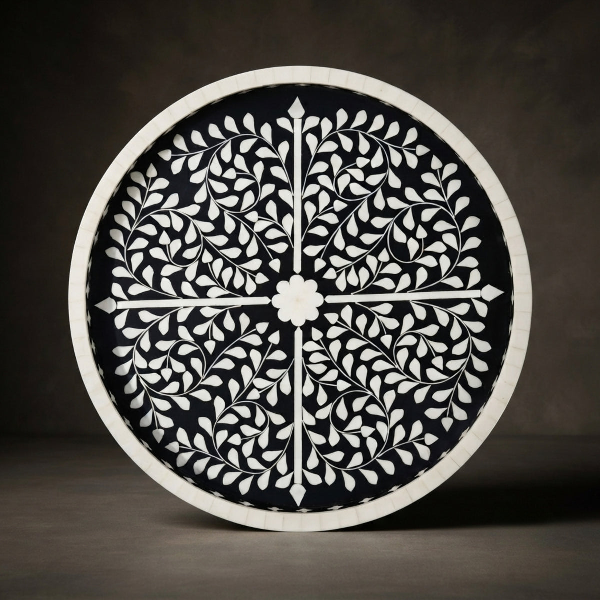 Round decorative wall mirror with a black and white floral inlay pattern, shown against a dark gray background.