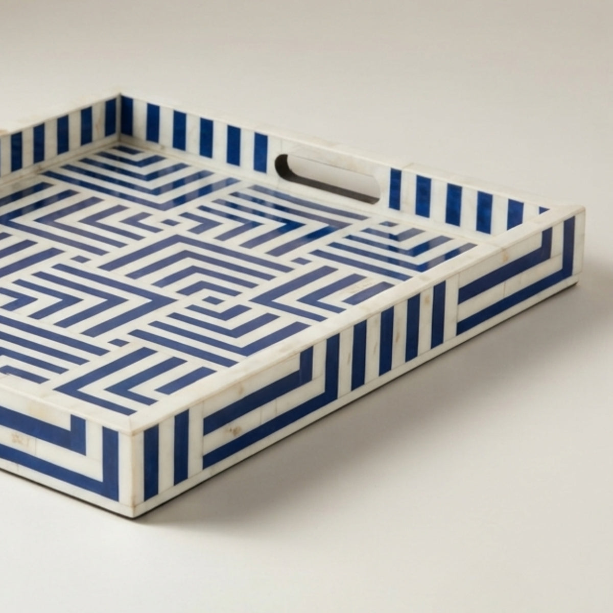 A rectangular serving tray with a geometric blue and white maze-like pattern, featuring integrated handles on the sides, shown on a neutral light gray background.