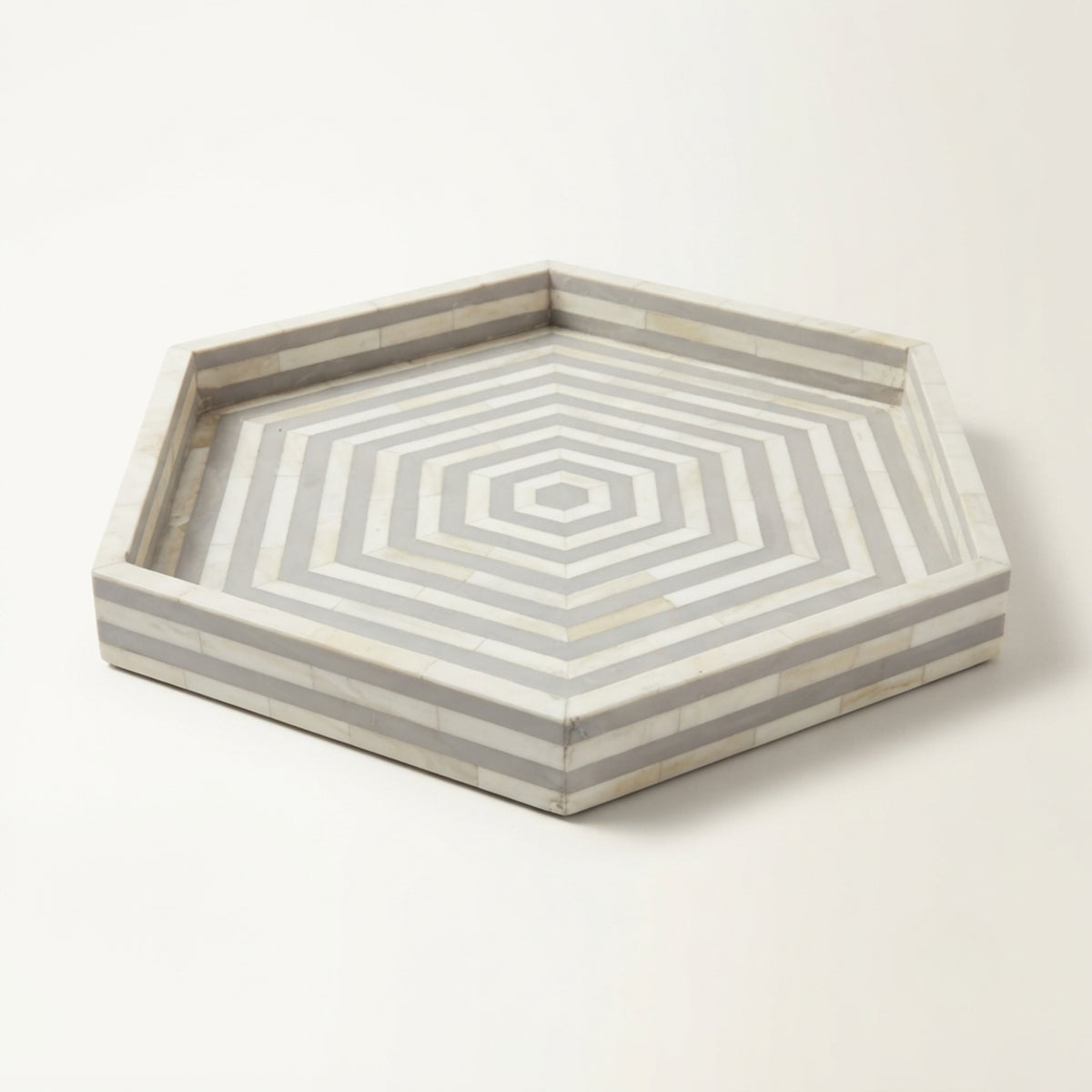 Hexagonal bone-inlay serving tray with concentric geometric patterns in light gray and off-white, shown on a clean white background.