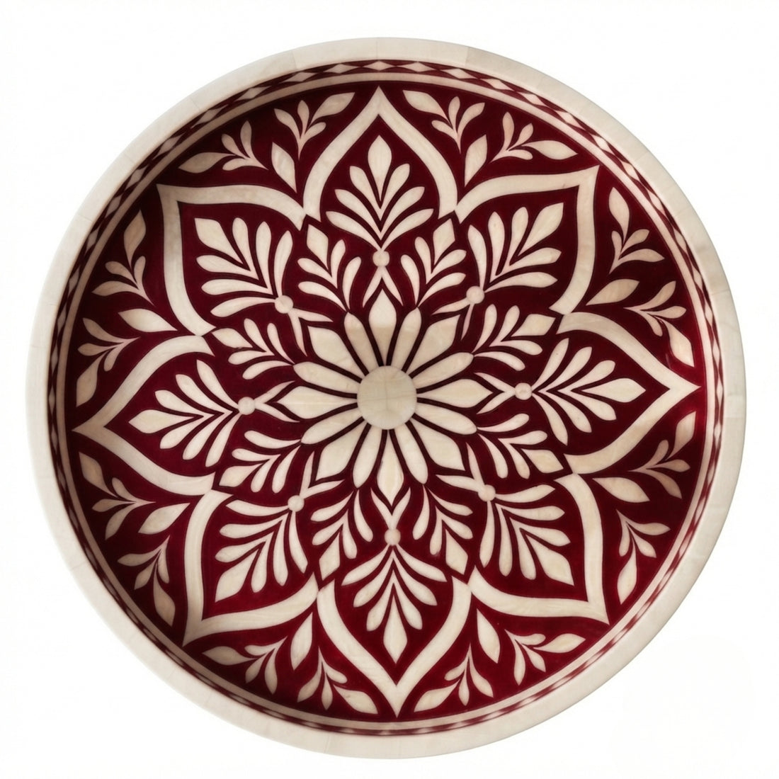 A set of hand-painted ceramic serving pieces, including a large round platter and two small bowls, featuring a detailed red and cream floral mandala pattern, arranged on a wooden table with decorative props.
