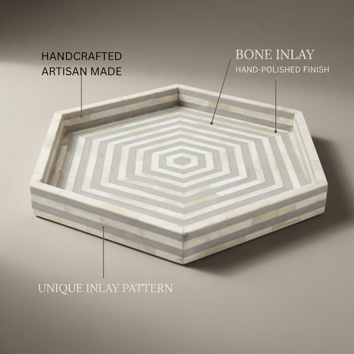 Hexagonal decorative tray with concentric geometric inlay pattern in off-white and light gray, shown on a warm taupe background with callout text reading 'HANDCRAFTED ARTISAN MADE,' 'BONE INLAY HAND-POLISHED FINISH,' and 'UNIQUE INLAY PATTERN.'.