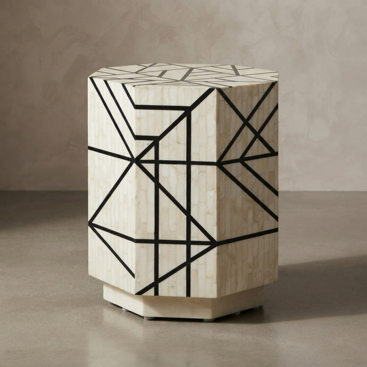 A geometric side table with a hexagonal shape, featuring a cream-colored bone or shell inlay pattern overlaid with black lines, set against a neutral textured beige background.