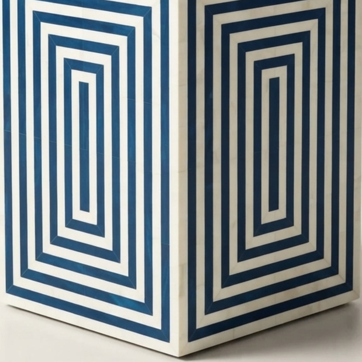 A close-up of a geometric storage box or container featuring a bold blue and white concentric rectangular pattern.