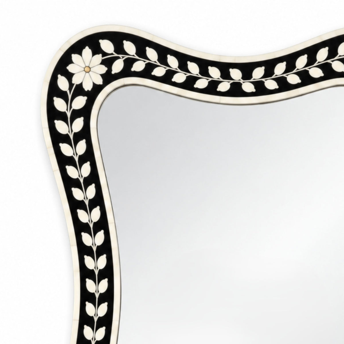A close-up of a decorative mirror frame with a black and white floral inlay border on a white background.