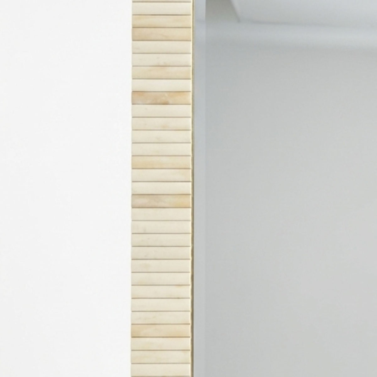 A close-up of a vertical slatted wooden panel in a light natural wood finish, positioned next to a plain light gray wall.