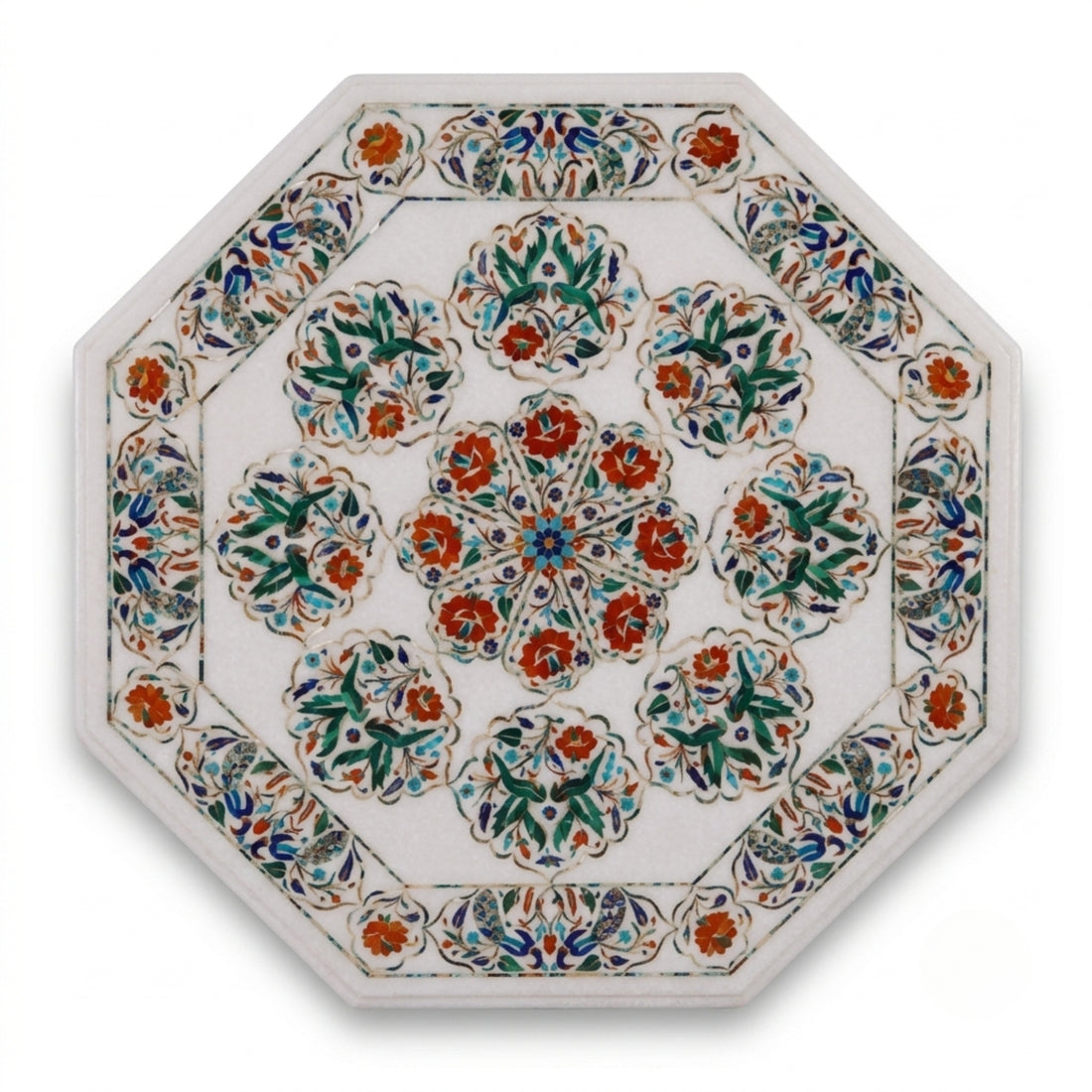 An octagonal side table with a mosaic tile top and a stone pedestal base, styled with a clear glass vase of white orchids, a book, and a candle in a sunlit interior corner.