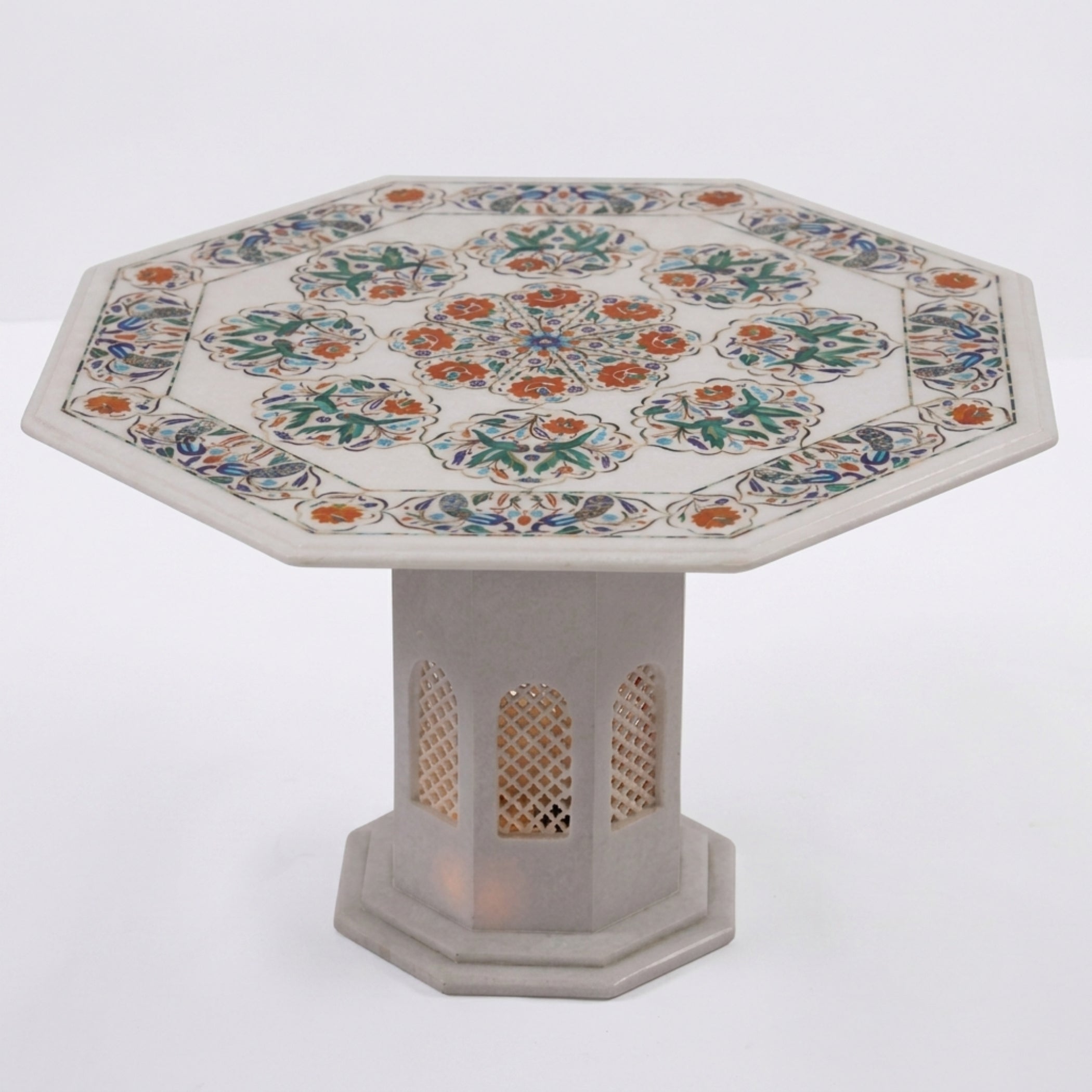 An octagonal stone table with a white marble base and a highly detailed, colorful inlay pattern featuring green, orange, and blue floral motifs on a white background.