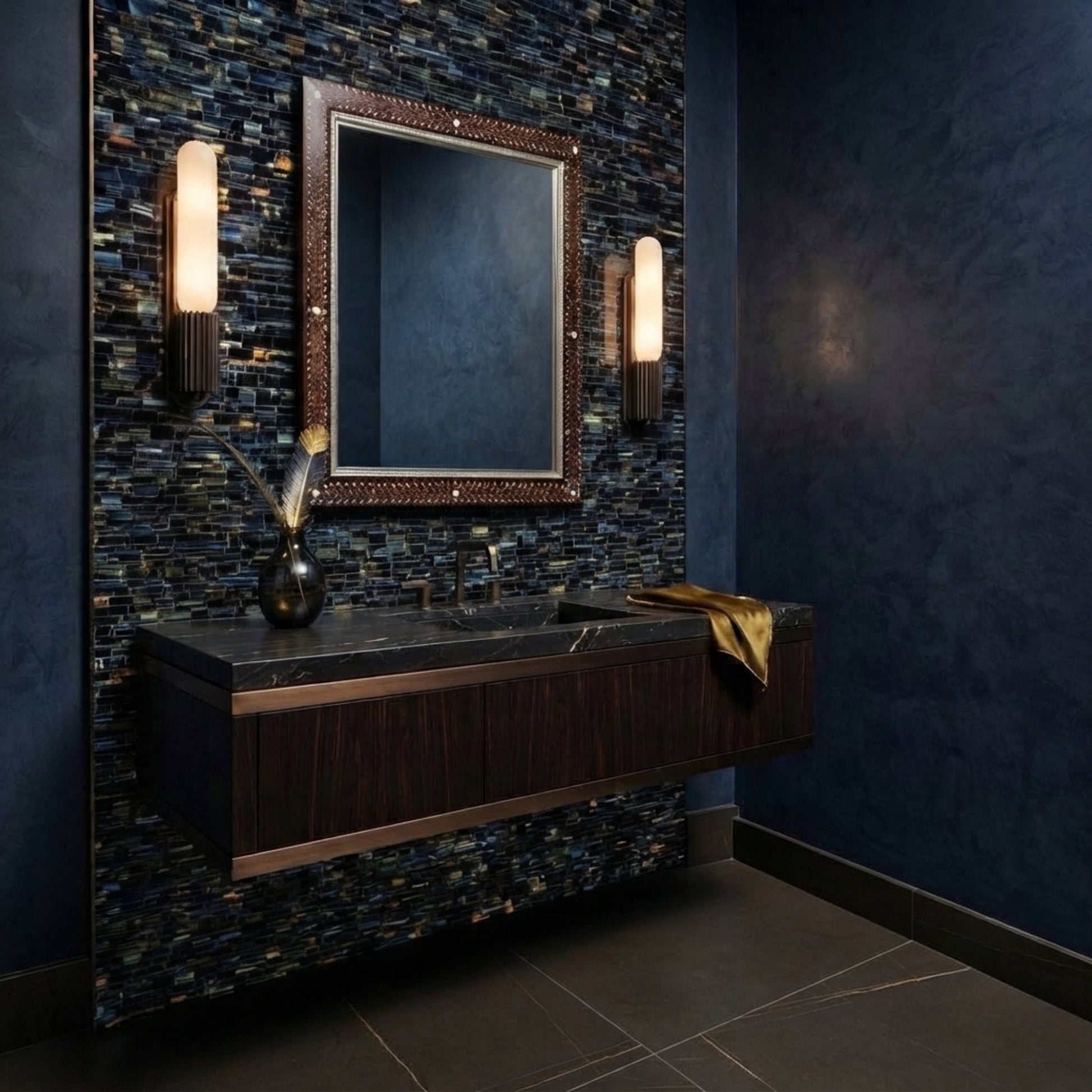 A modern floating bathroom vanity with a dark wood cabinet, integrated sink, and a large decorative mirror, set against a blue mosaic tile wall with wall-mounted sconces.